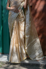 Load image into Gallery viewer, A woman wearing a gold and red handwoven Chanderi tissue silk saree with tassels on pallu and contrasting stripes, standing in front of a green door.